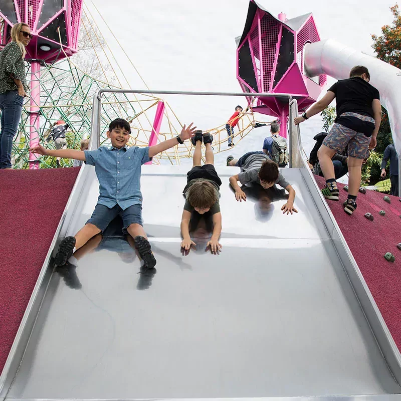 children sliding down a commercial playground slide in australia