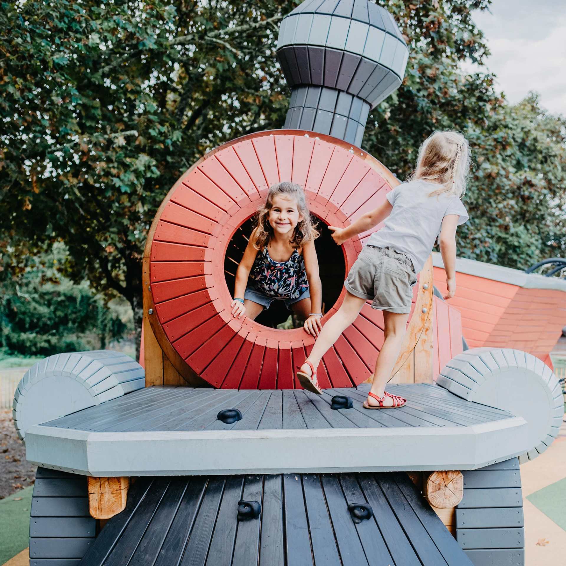 Children playing on a natural wood train play structure