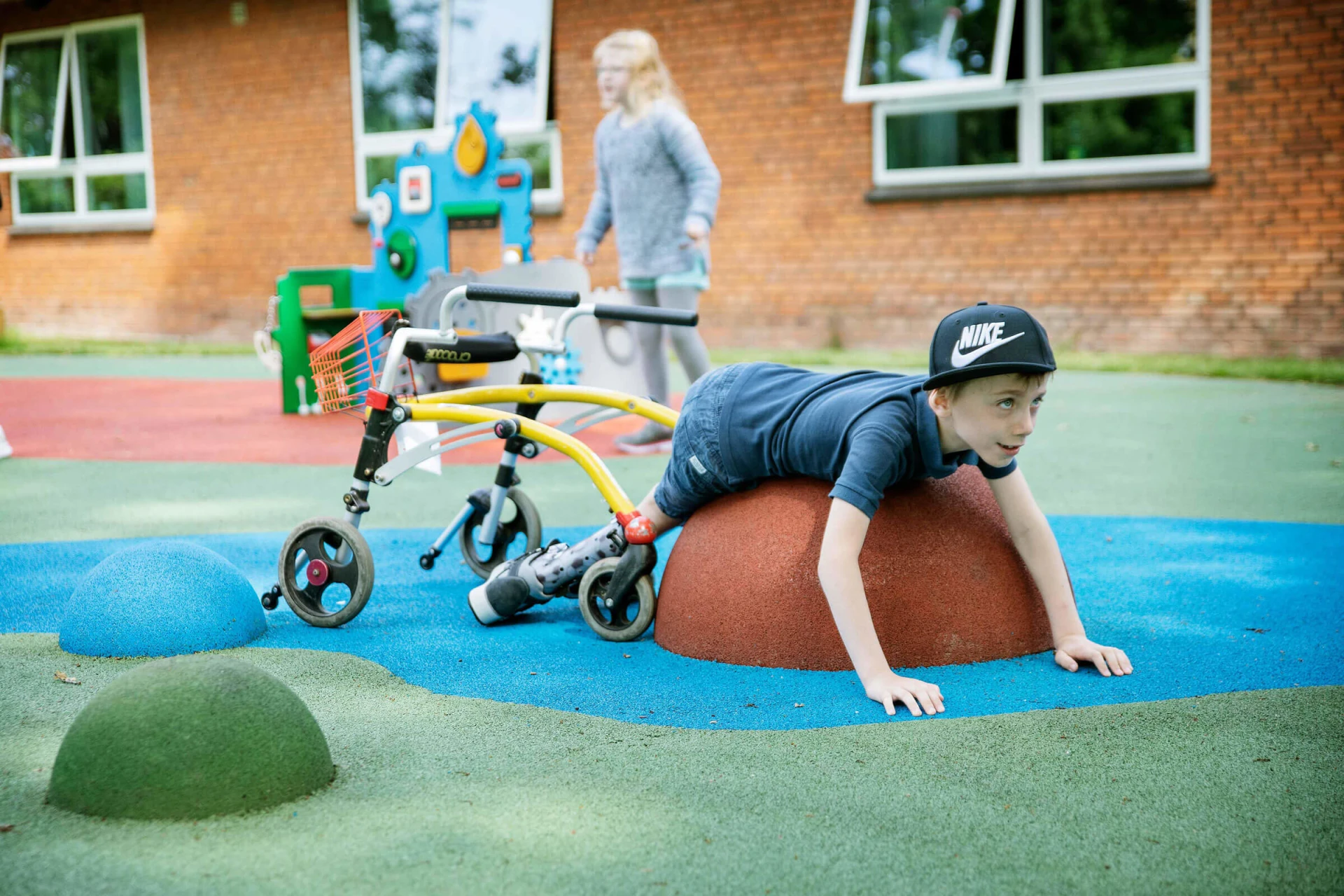 pojke med rollator leker på flexotop fallskyddsunderlag på lekplats