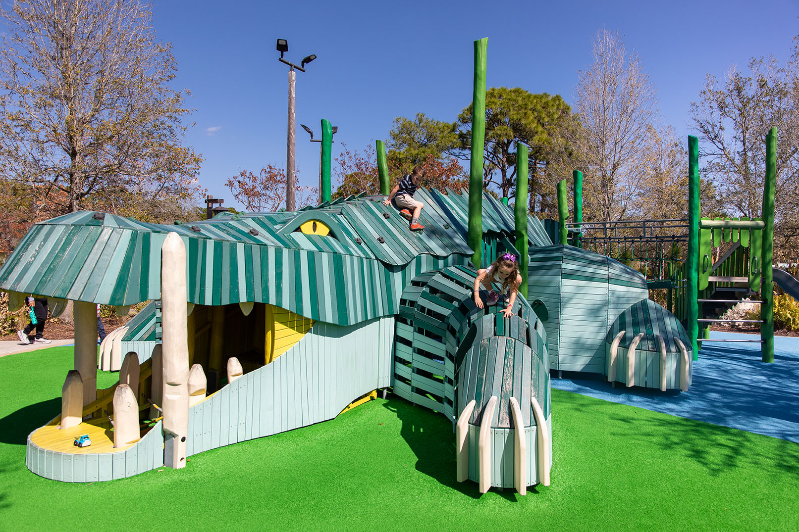 At Pioneer Park in Port St. Lucie, Florida, two elementary-aged children playing on a custom, alligator-themed wooden playground structure.