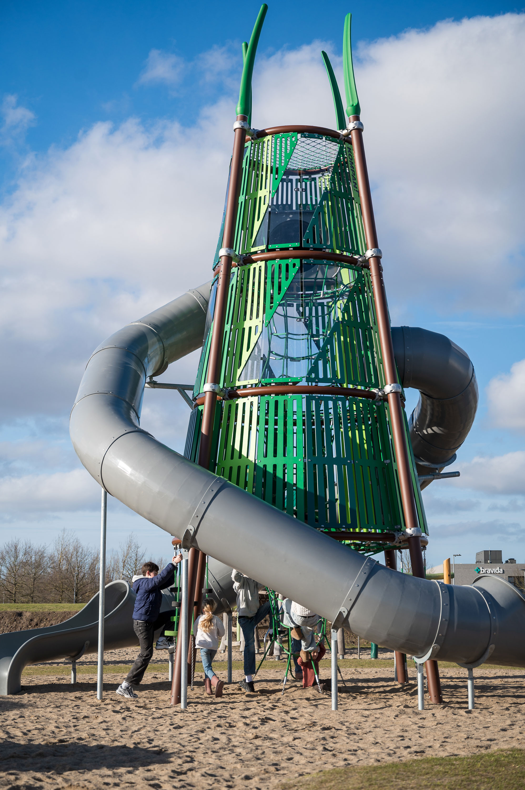 large playground tower and children climbing up to the slides