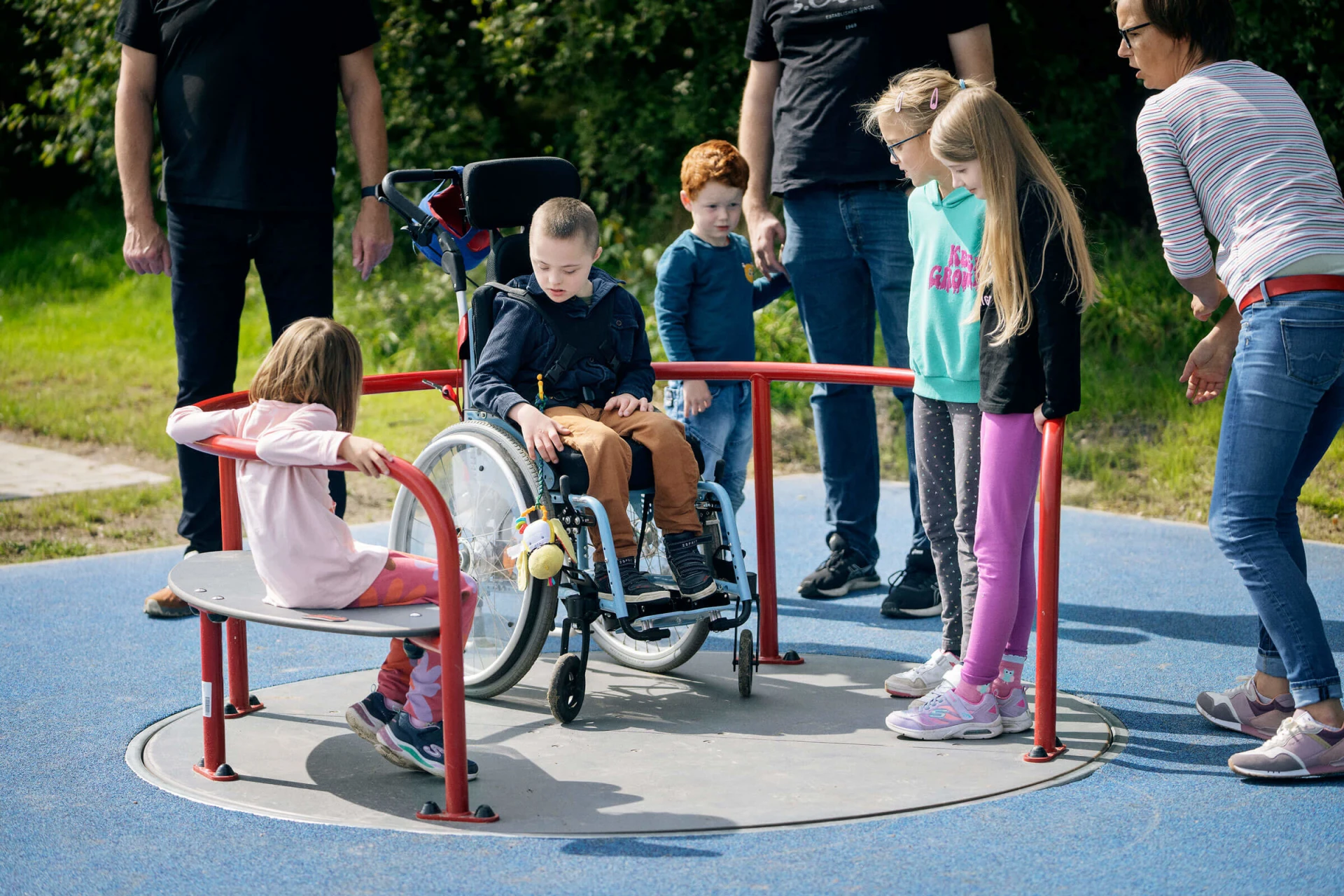 Niños jugando en un carrusel de sillas de ruedas en un parque infantil