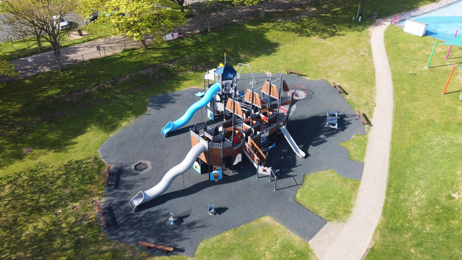 Aerial view of a large pirate ship playground with slides and climbing frames on soft flooring, surrounded by grass and paths