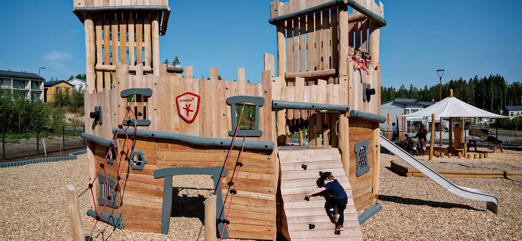 Wooden playground castle with boy climbing up a climbing wall at Porvoo