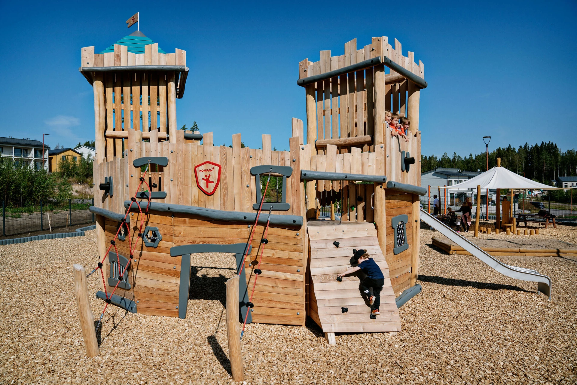 Wooden playground castle with boy climbing up a climbing wall at Porvoo