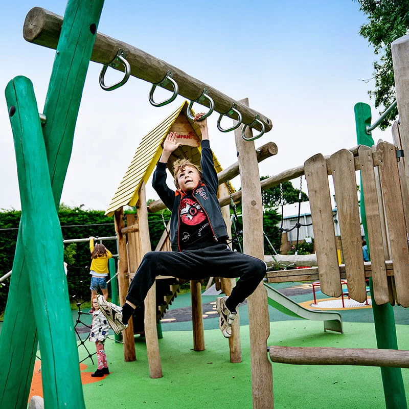 Et barn som leker på et lekesystem av Robinia-tre