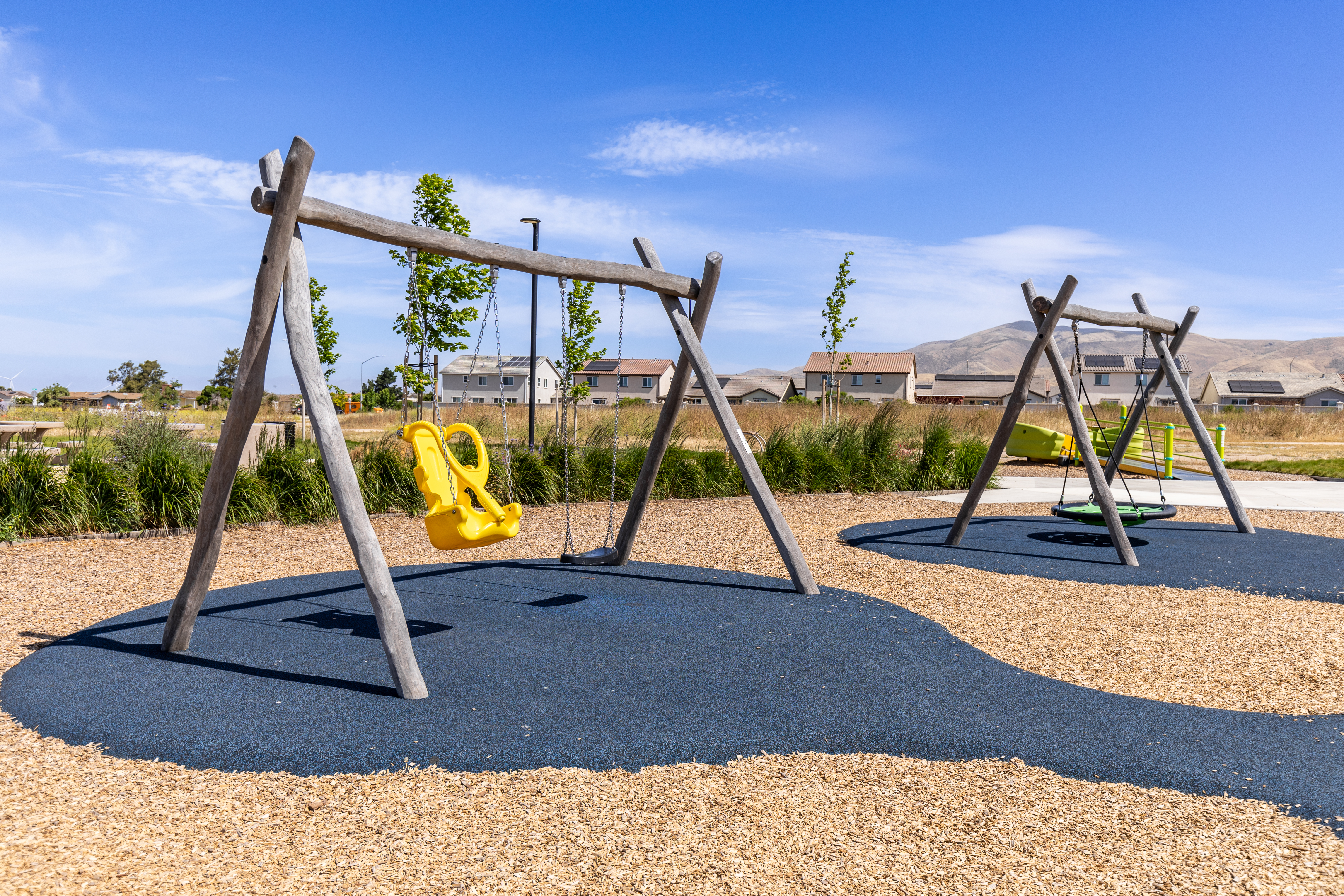 Commercial wooden swing set with an inclusive swing seat at a park in Fresno, California on a sunny day