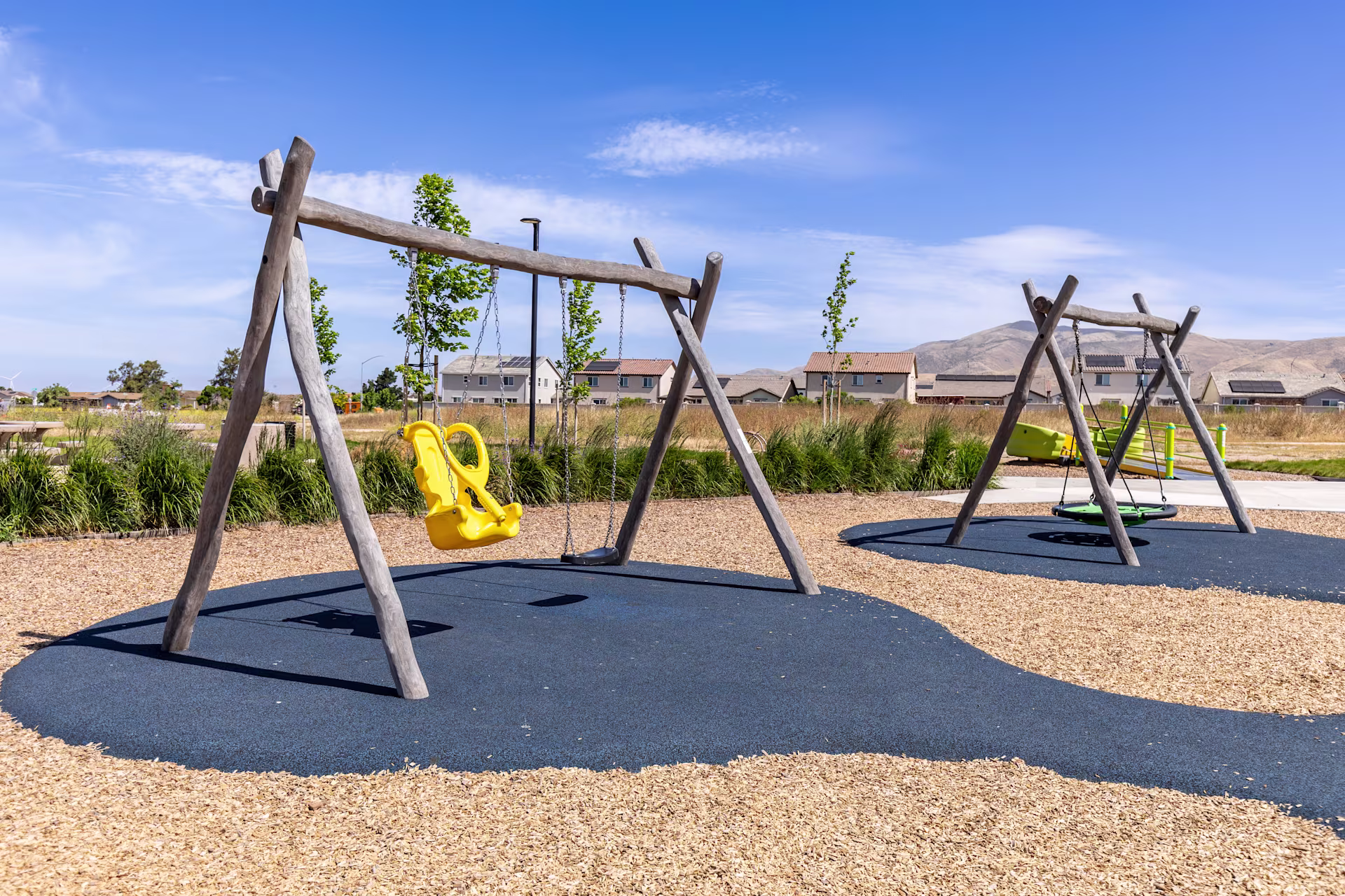 Commercial wooden swing set with an inclusive swing seat at a park in Fresno, California on a sunny day