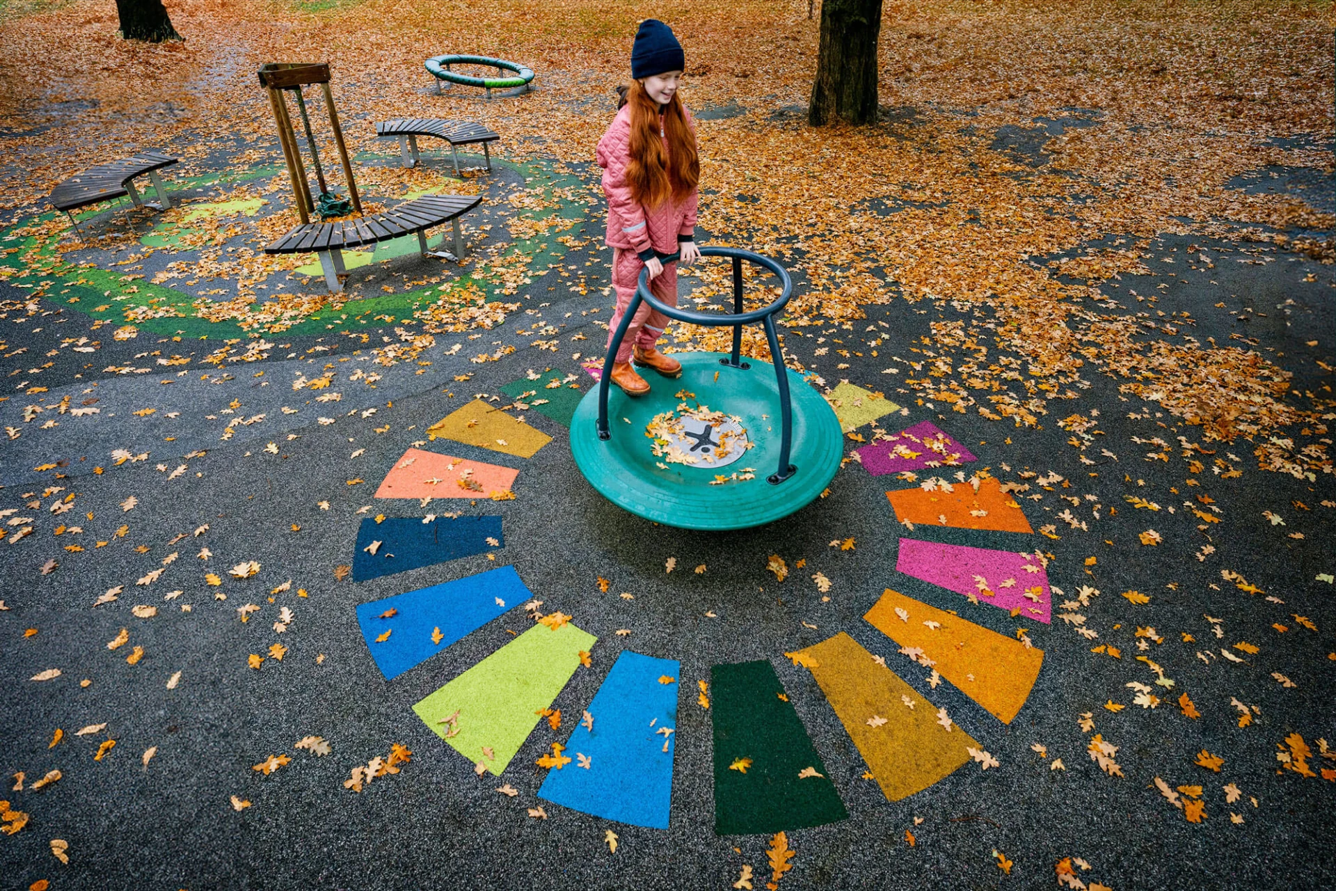 girl playing on playground spinner with colourful surfacing