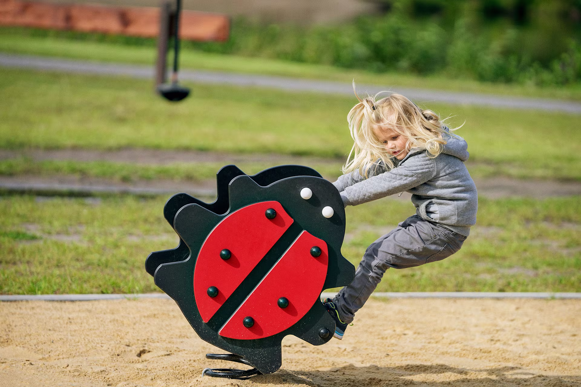 Mädchen wippt auf einem Marienkäfer Federwippgerät