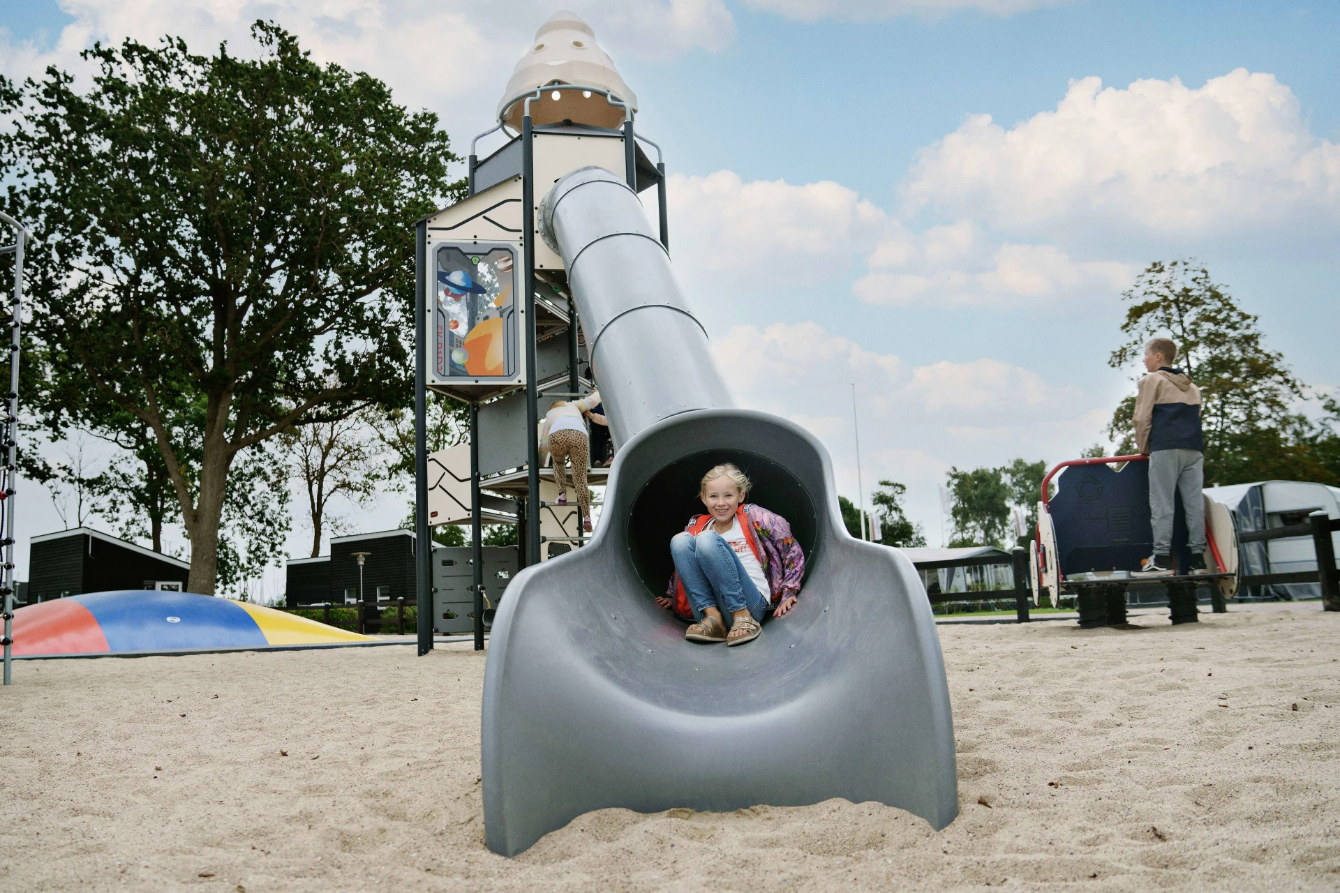 Girl sliding down from a space theme playground tower at CampOne Assens