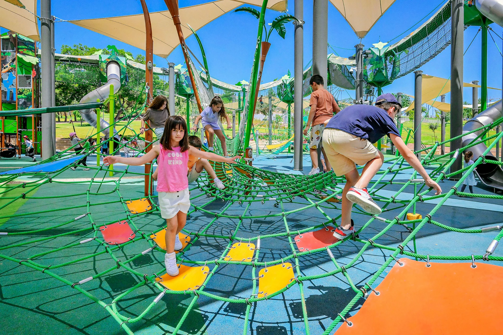 Children walking across a rope net play structure