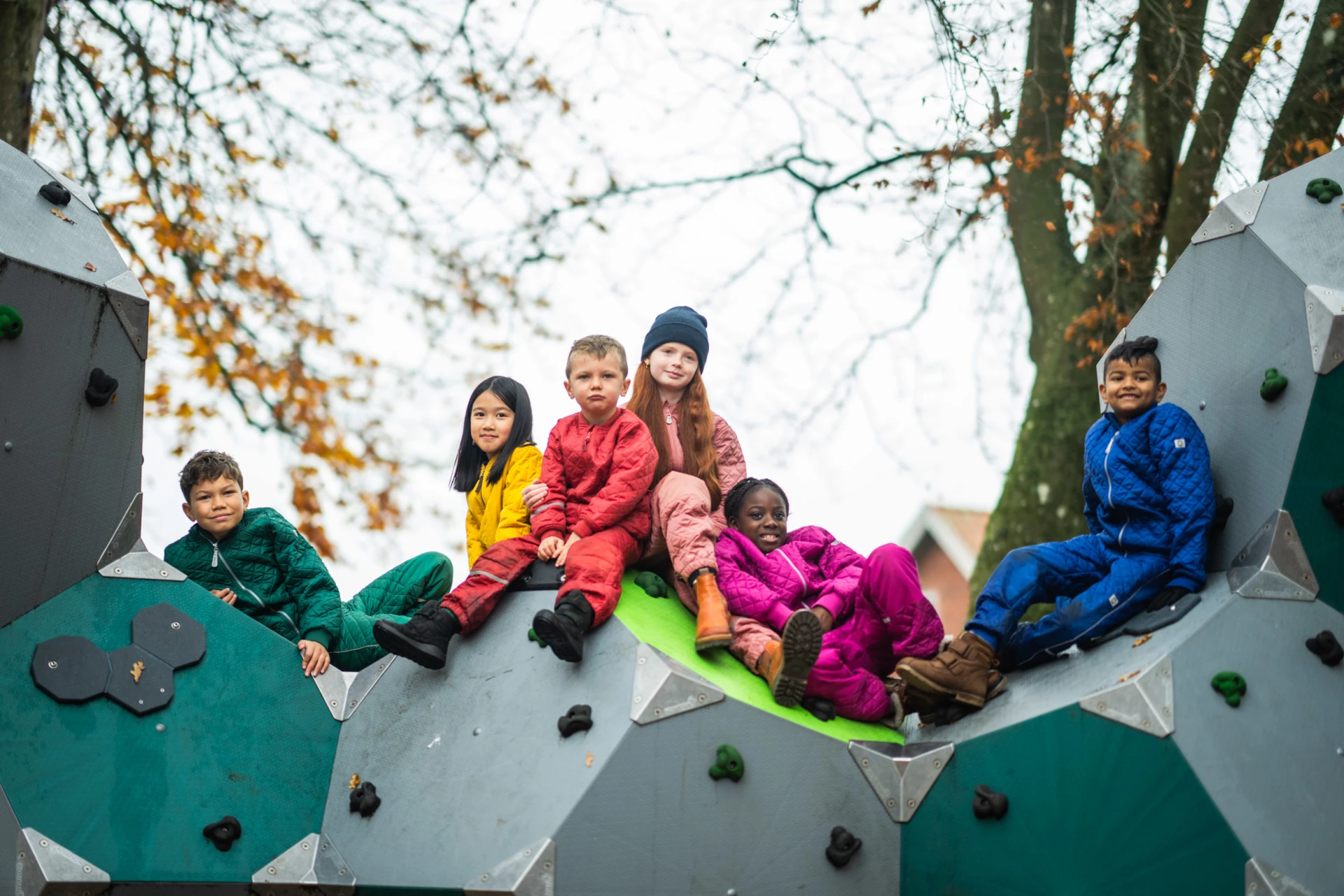 een groep kinderen zittend op een klimstructuur op een speelplaats