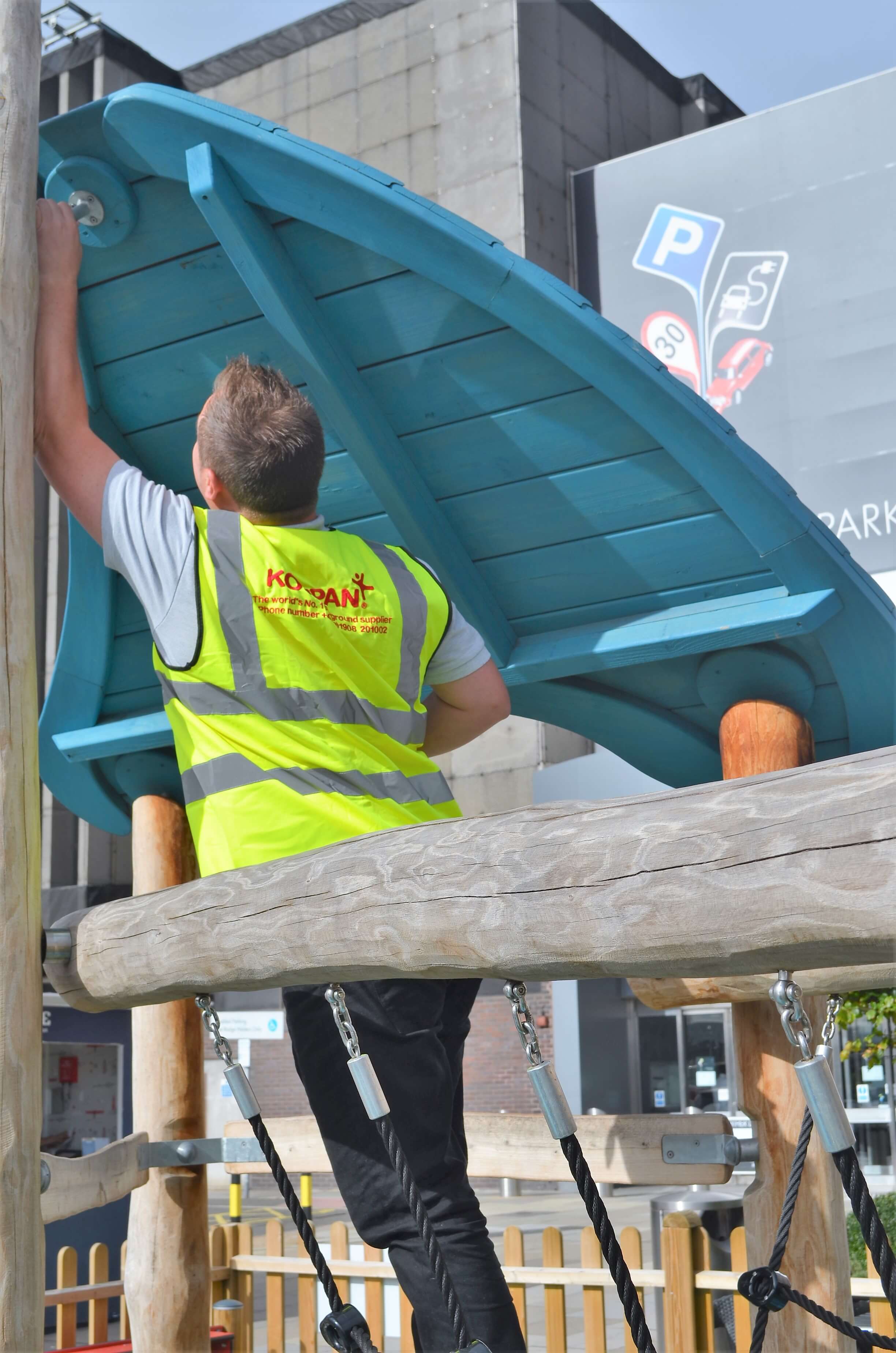 A man in a yellow vest working on a wooden structure