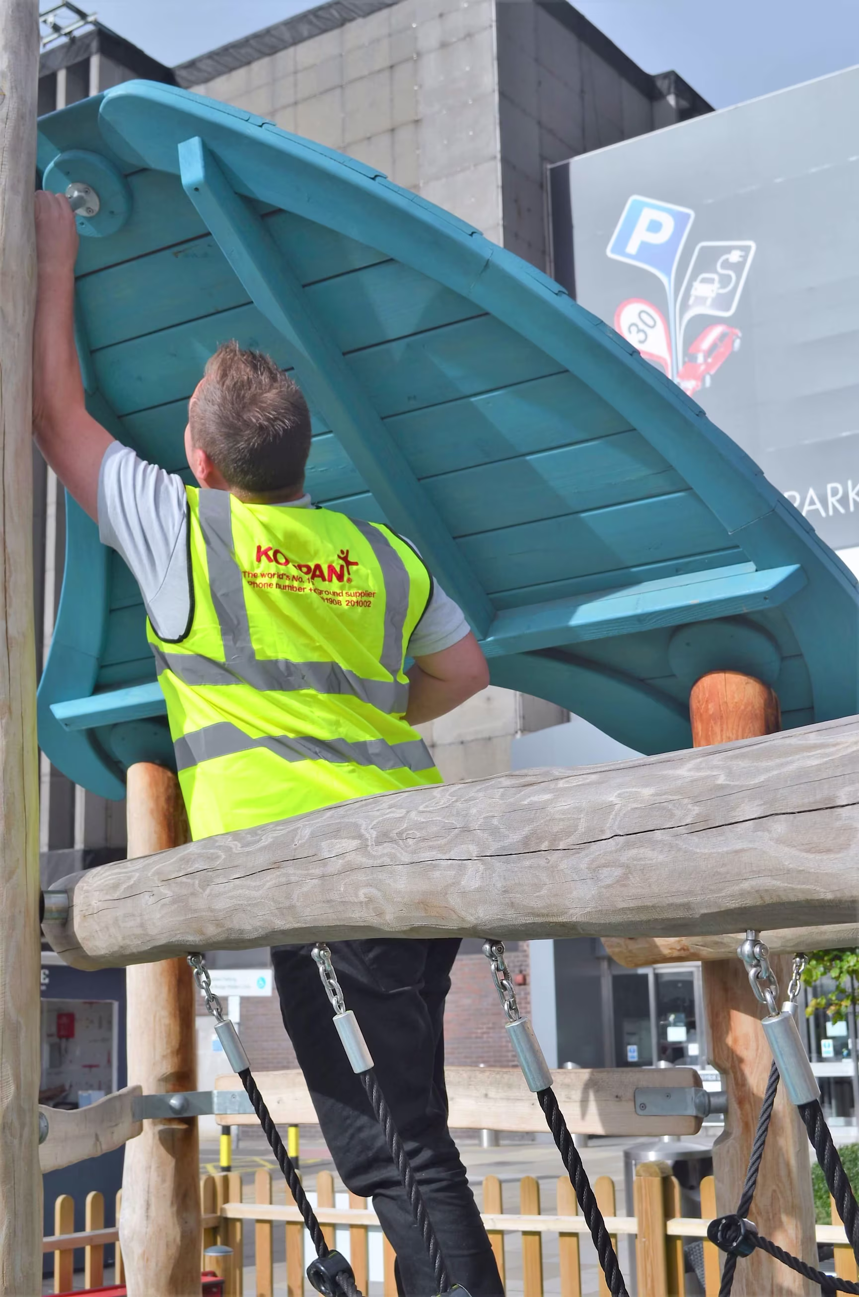 A man in a yellow vest working on a wooden structure