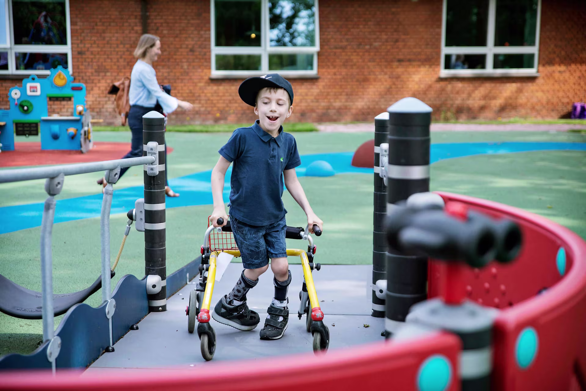 boy with walker using a ramp to get on a play tower
