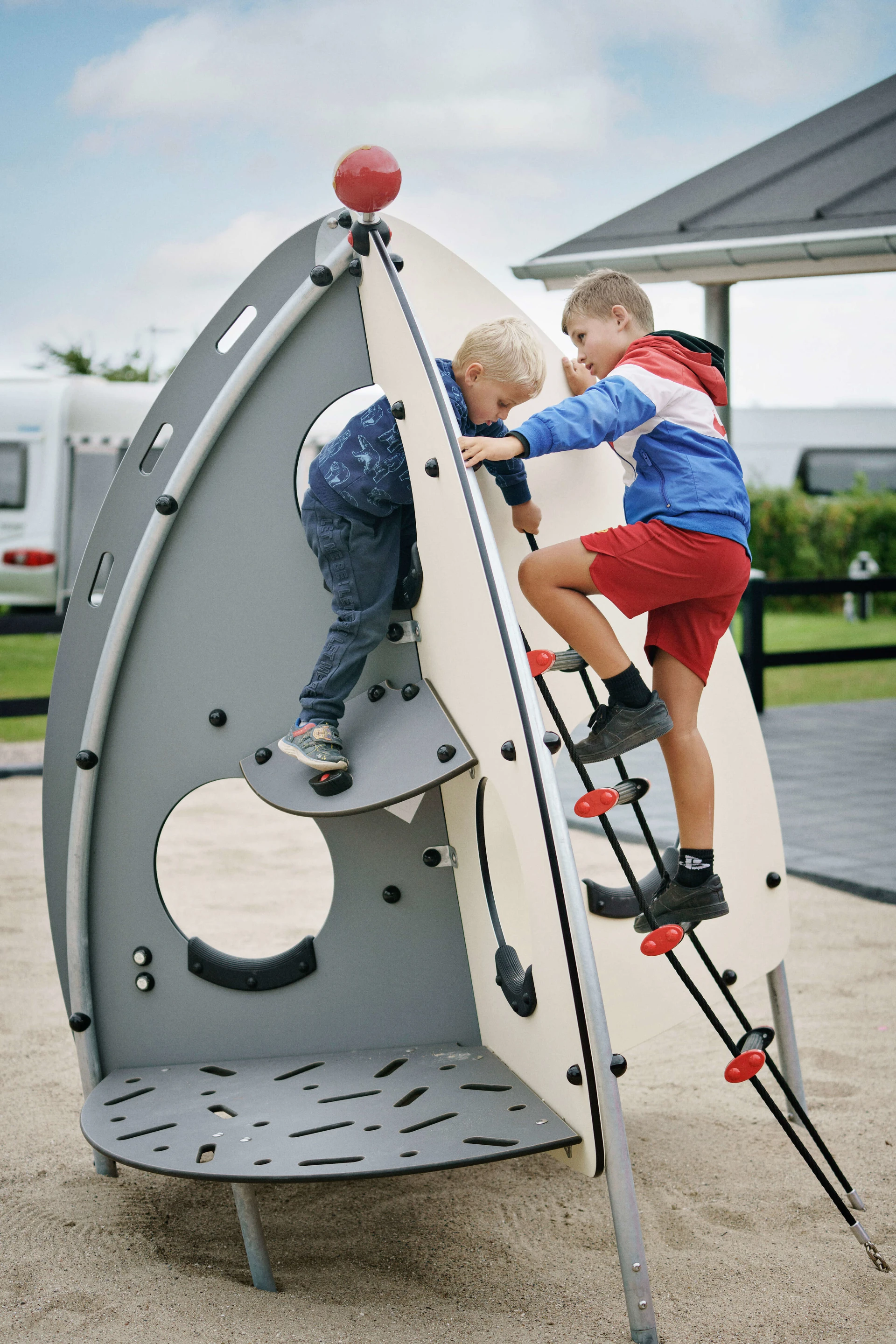 Two young boys playing on space themed playground equipment. Themes and design styles are important considerations for any playground plan. 