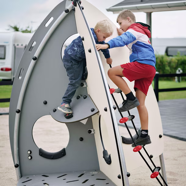 Two young boys playing on space themed playground equipment. Themes and design styles are important considerations for any playground plan.
