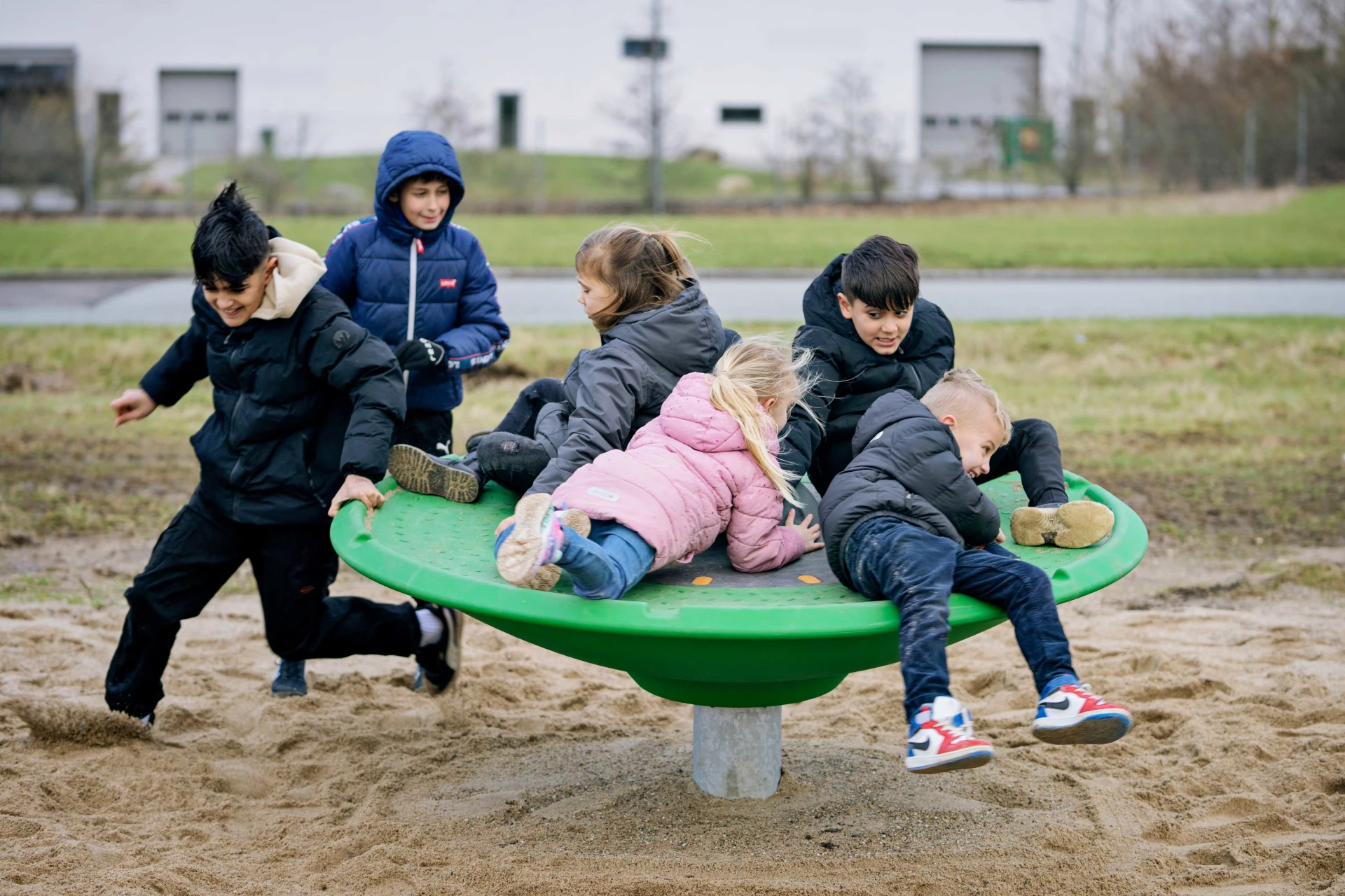 Kinder spielen auf der KOMPAN Spinner Disc Drehscheibe