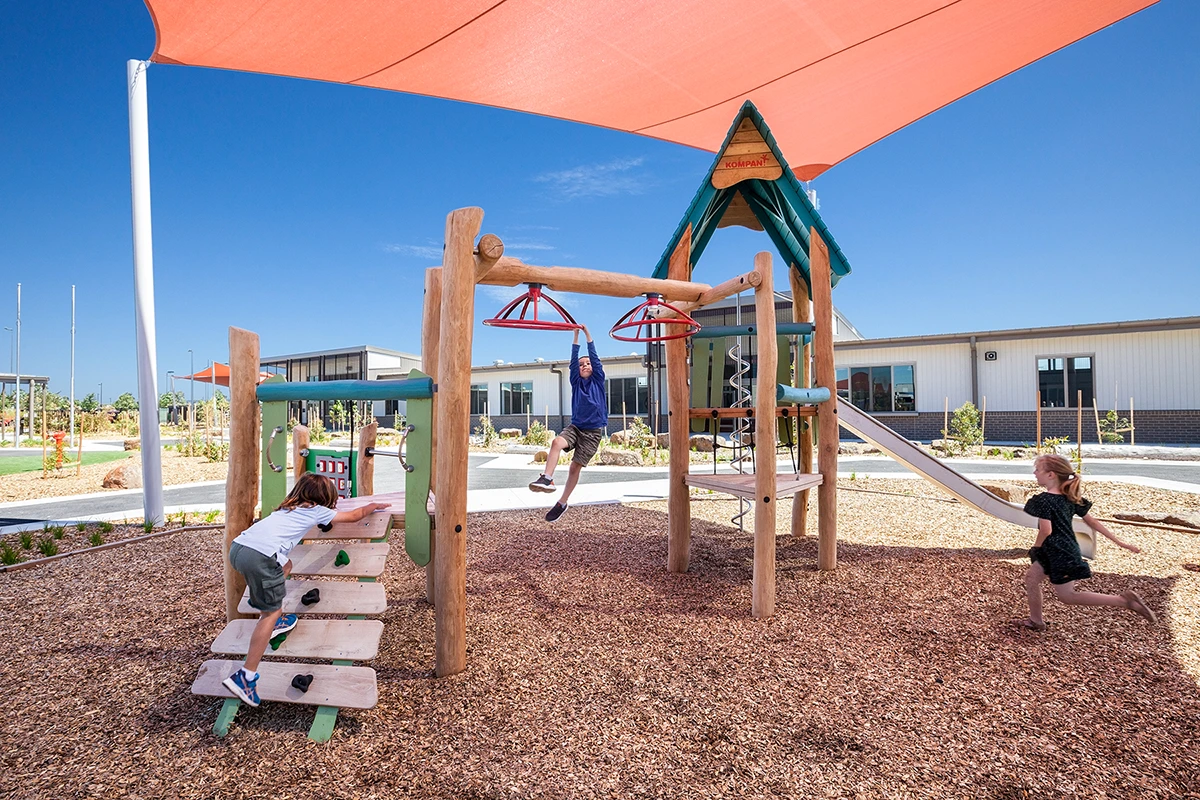 Kids playing on a large natural playground structure 