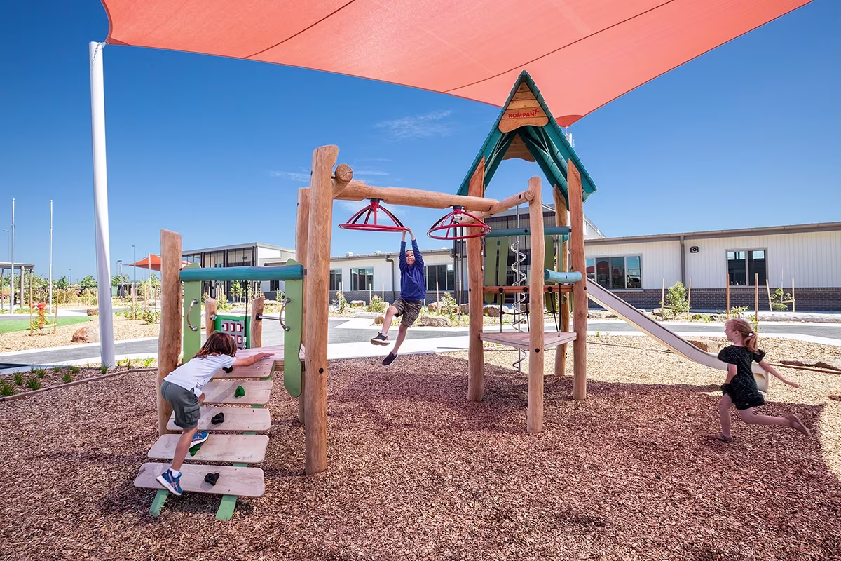 Kids playing on a large natural playground structure 