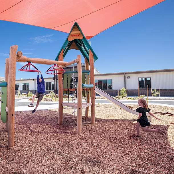 Kids playing on a large natural playground structure