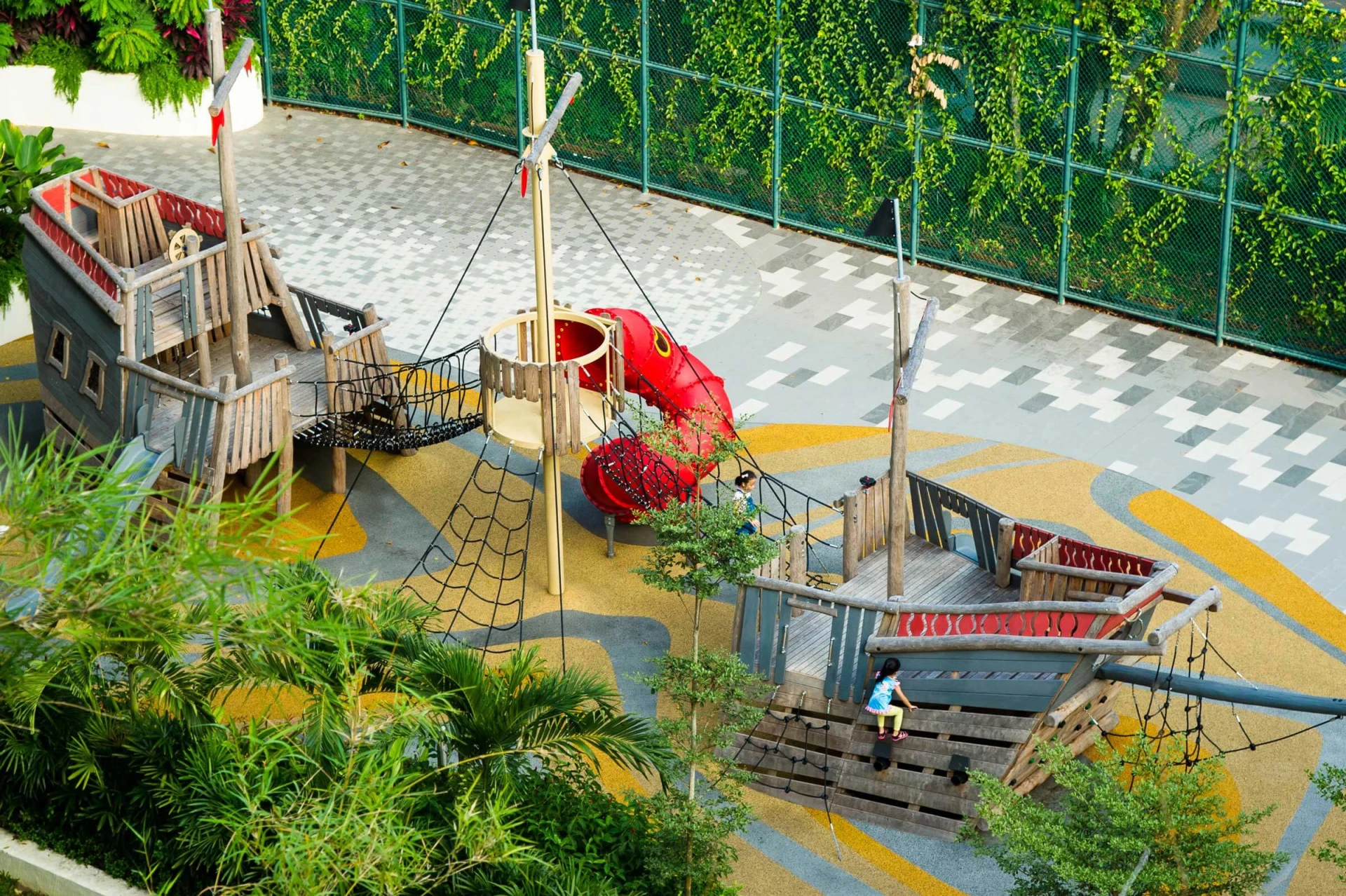 A large wooden playground ship with a climbing net and slide