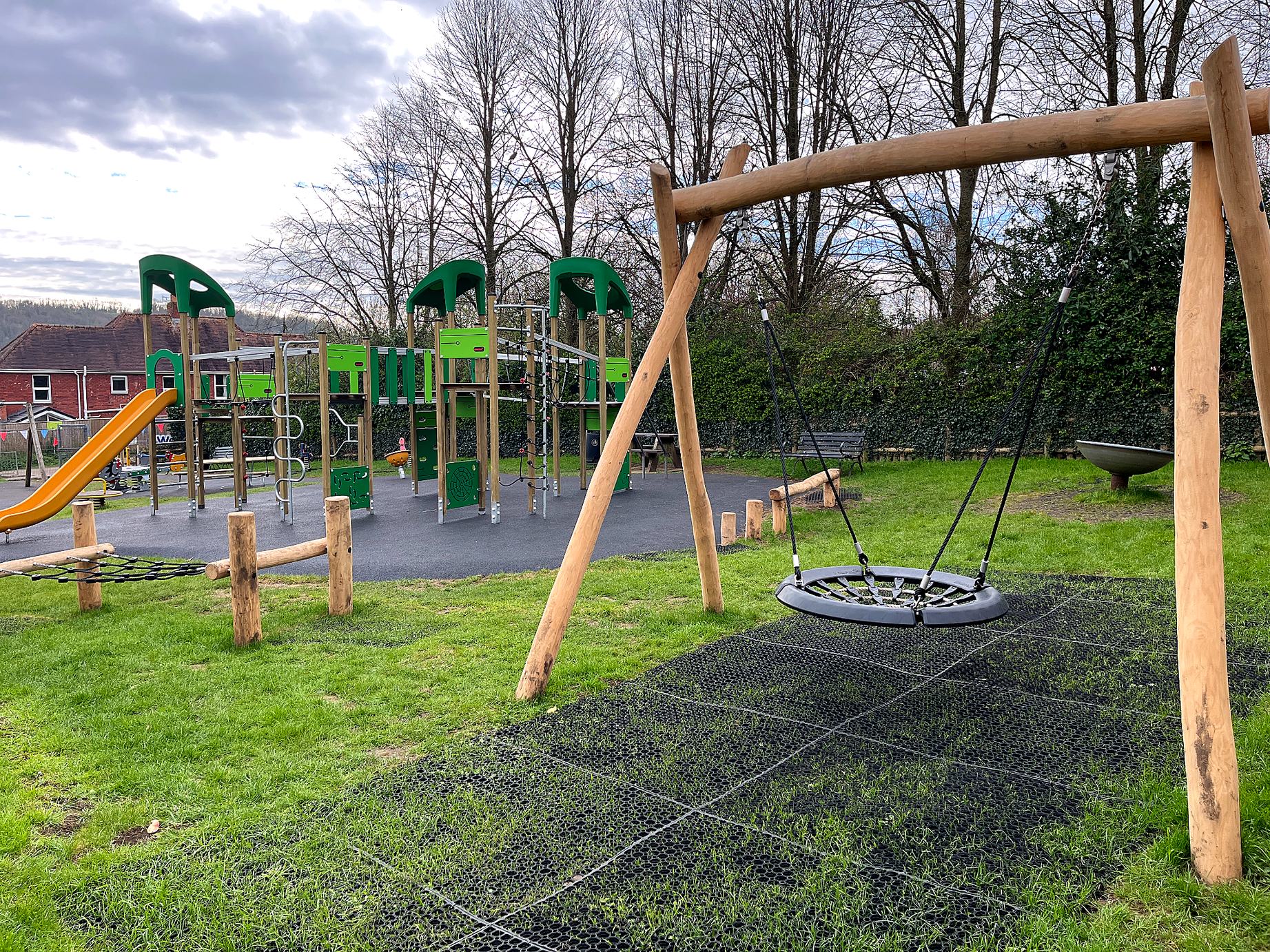 wooden basket swing with green climbing frame with yellow slide