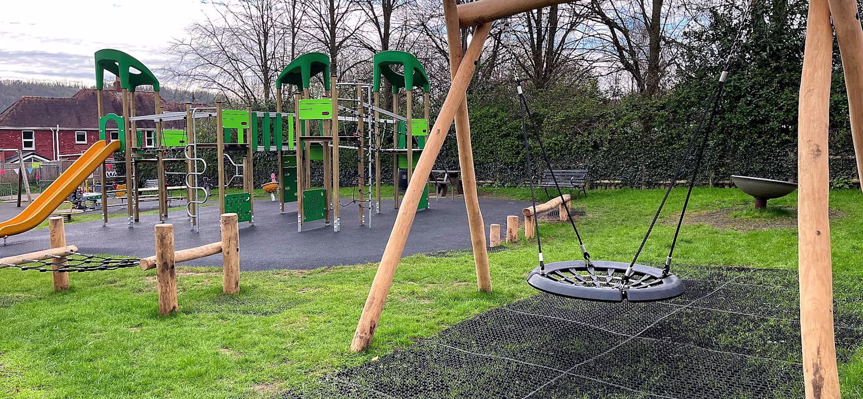 wooden basket swing with green climbing frame with yellow slide