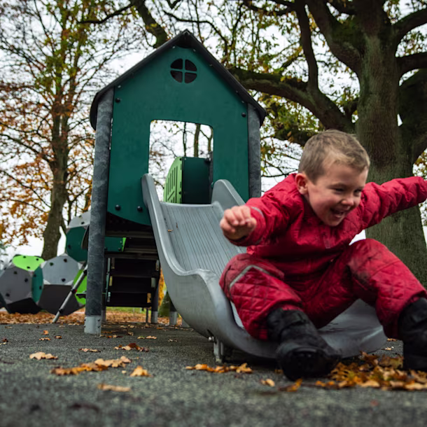 ragazzo che scivola su uno scivolo in una struttura del parco giochi
