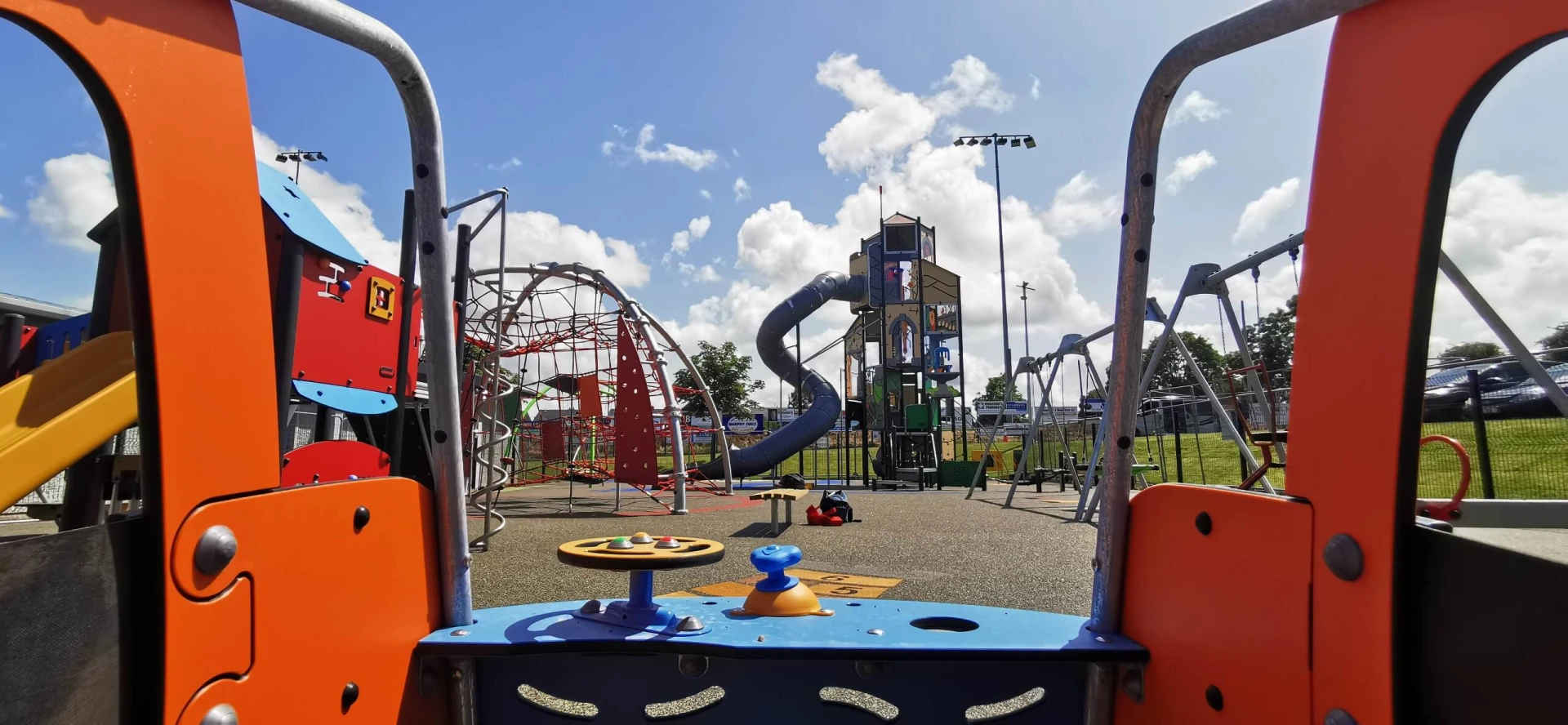 A view of a playground with a slide and swings.