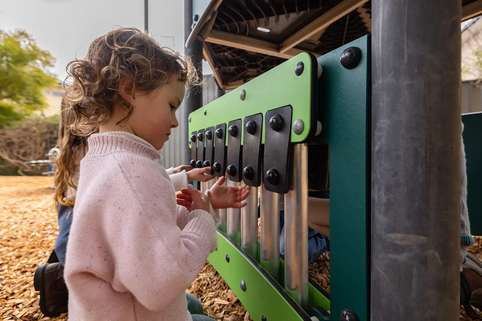 two girls playing on a musical playground panel