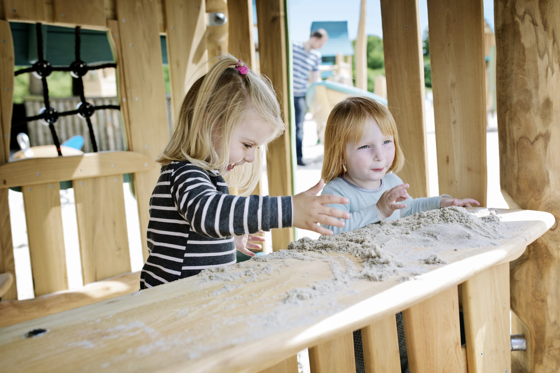 two small girls playing with sand at a wooden playhouse in Givskud Zoo