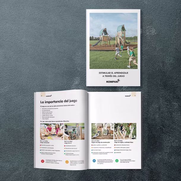 Two brochures on a dark surface, one closed showing kids playing on a playground, one open with Spanish text and photos of children.