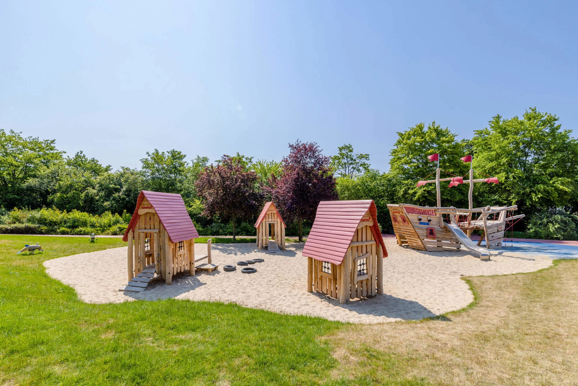 Holzspielplatz in einem Kindergarten mit kommerziellen Spielhäusern und Holzschiff