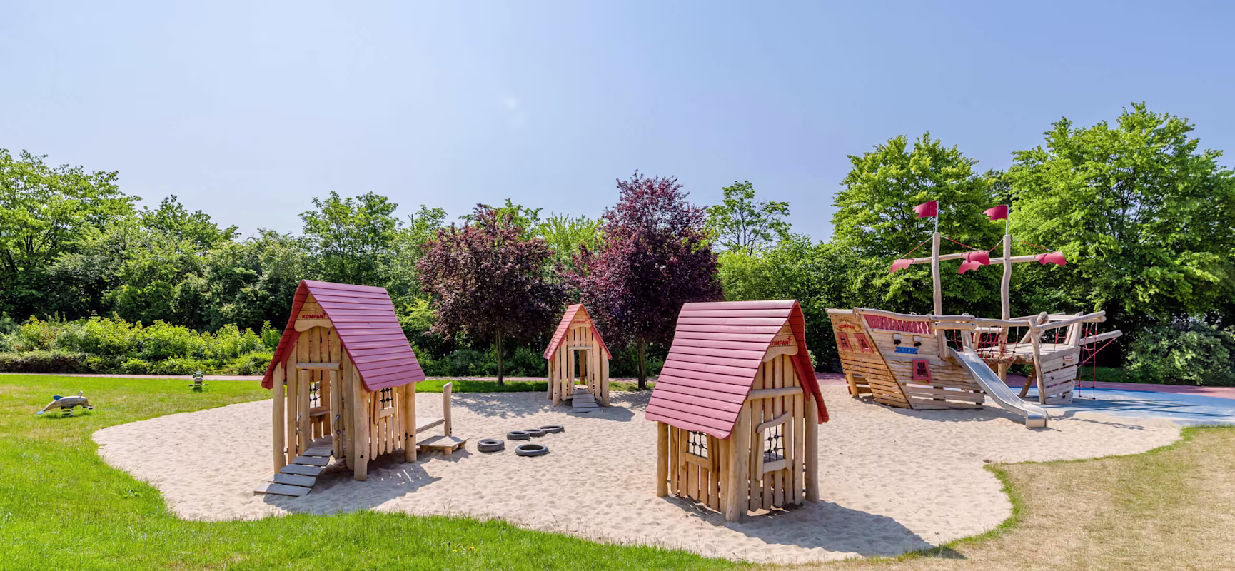 Holzspielplatz in einem Kindergarten mit kommerziellen Spielhäusern und Holzschiff