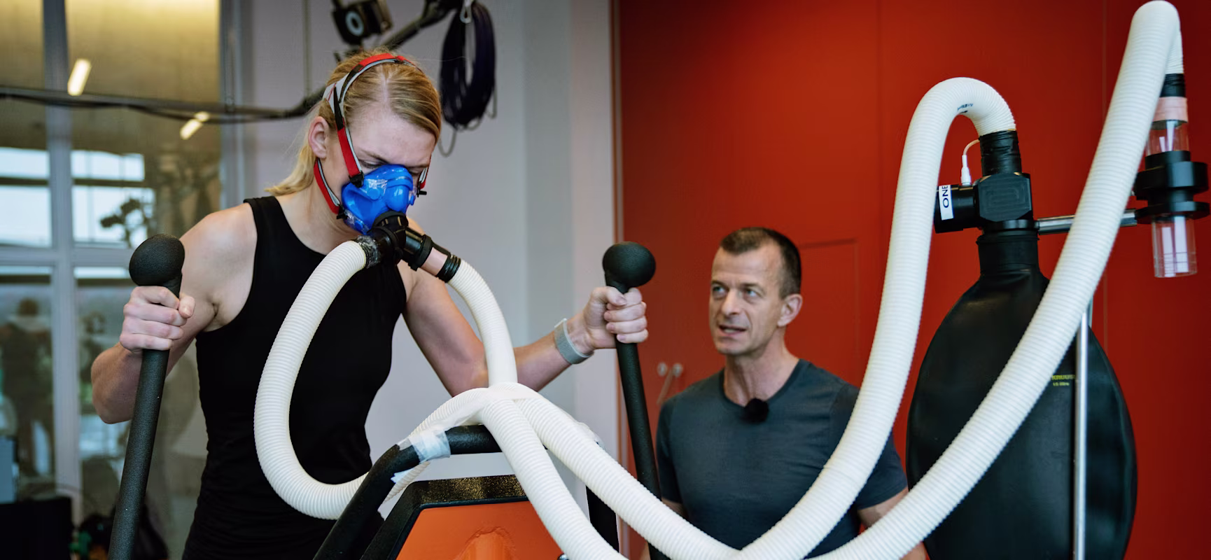 En mann og en kvinne i et treningsstudio tester KOMPAN crosstrainer.