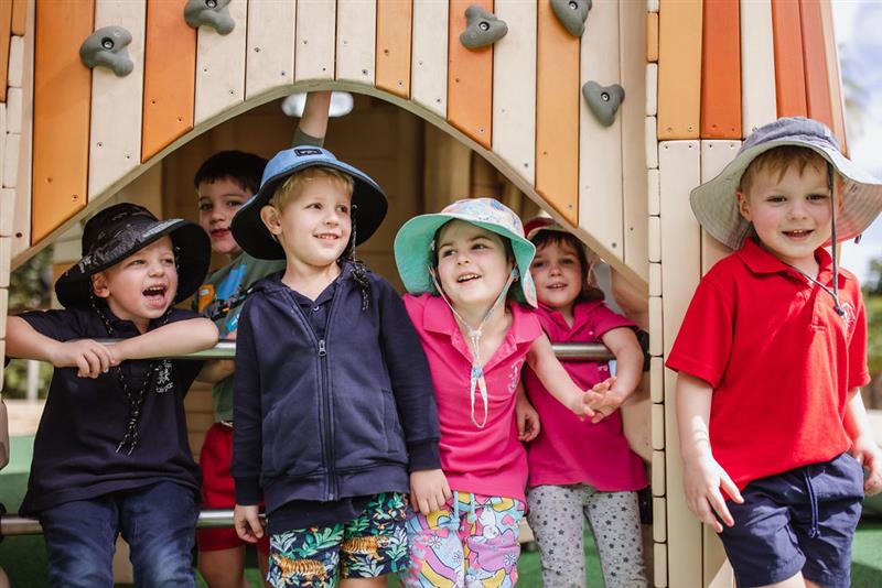 Children playing on kindergarten playground equipment in wood