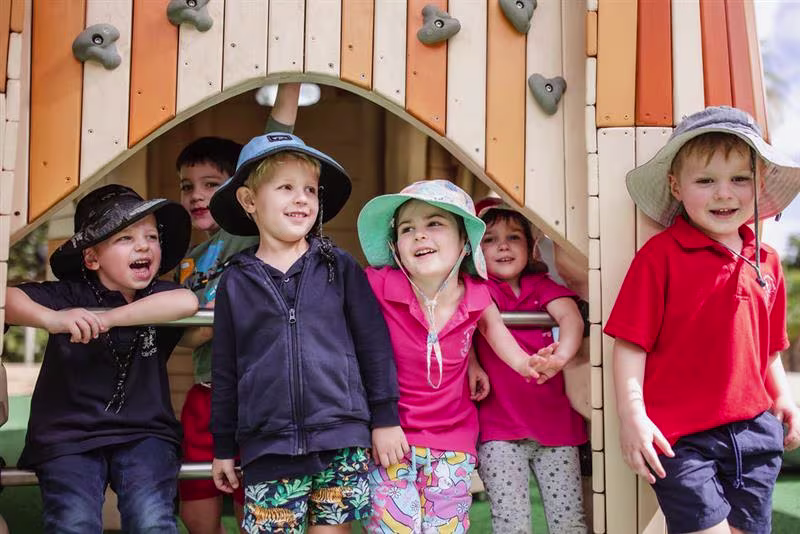 Children playing on kindergarten playground equipment in wood