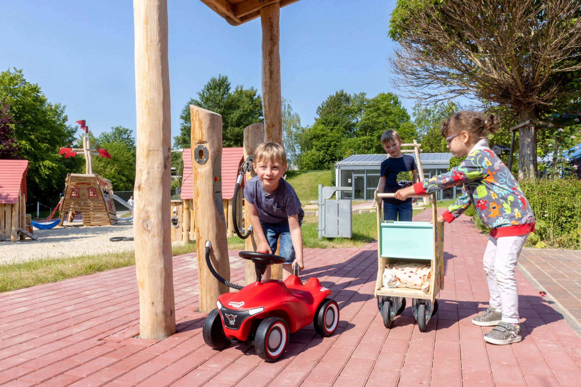 Kinder spielen auf einem Kindergartenspielplatz mit Holzgeräten