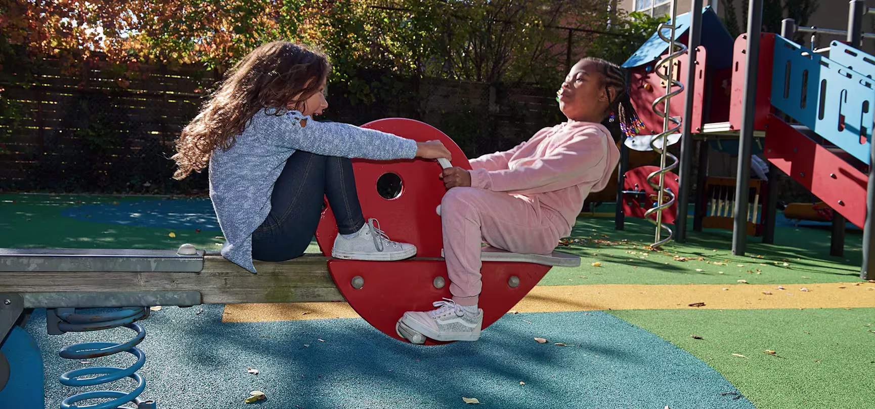 hero of girls on a seesaw in a public park playground