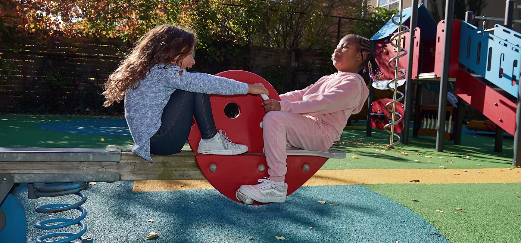 hero of girls on a seesaw in a public park playground