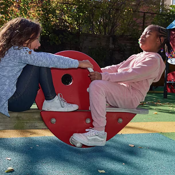 hero of girls on a seesaw in a public park playground