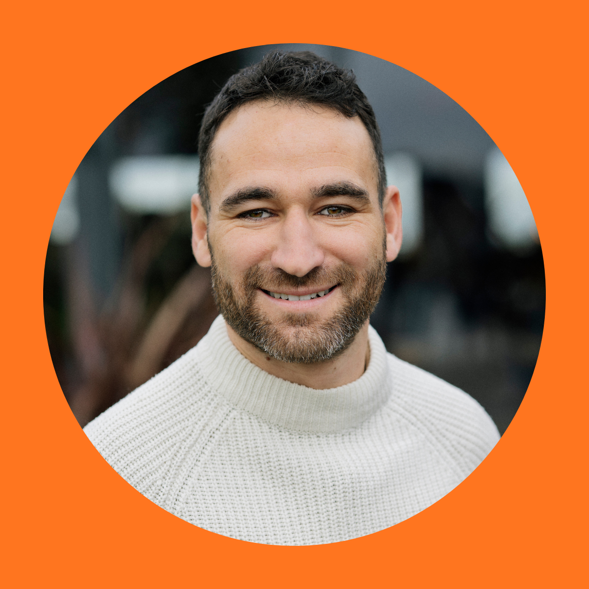 Portrait of a person in a white knitted sweater, face blurred, against a dark outdoor background within an orange circular frame