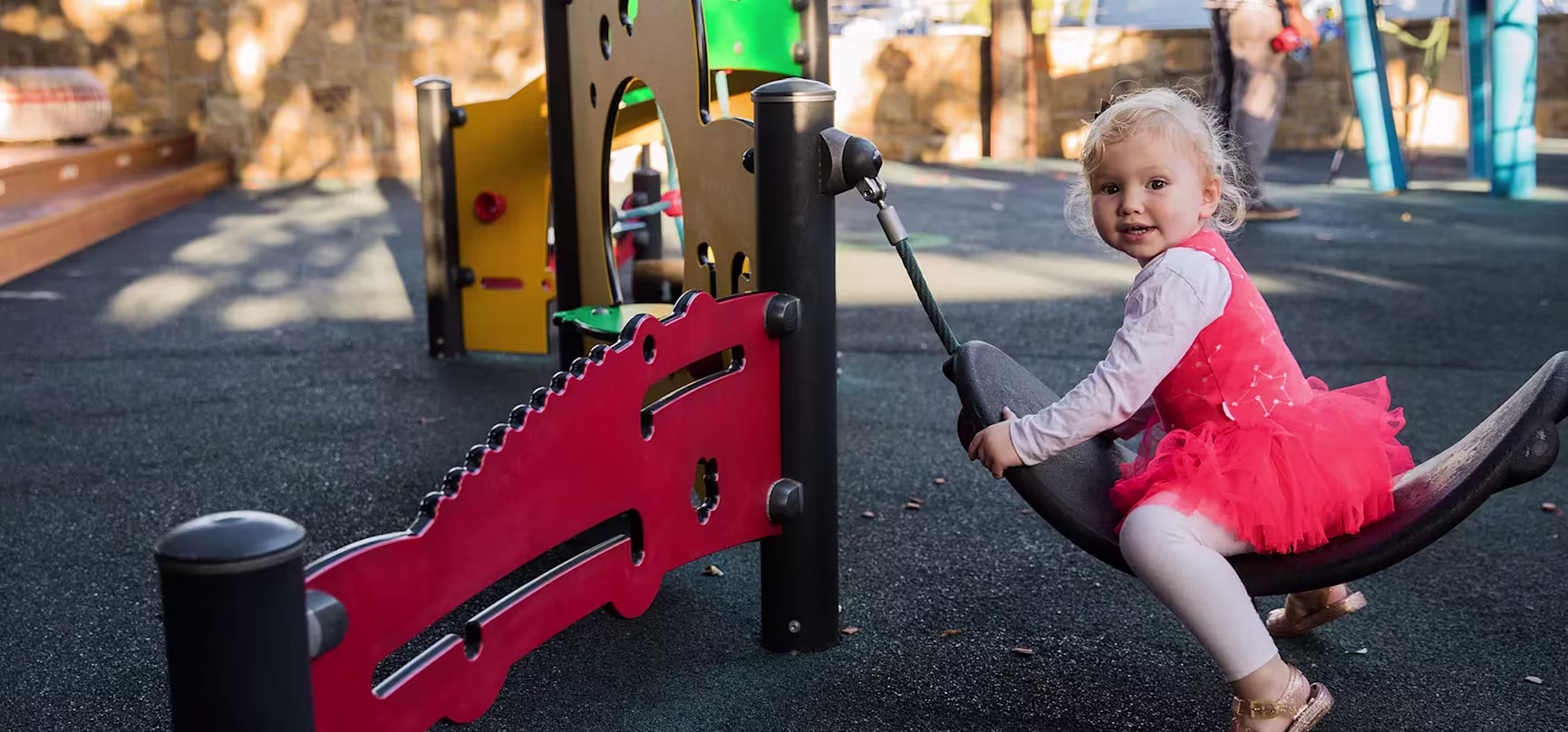 toddler playing on playground equipment for toddlers in a park