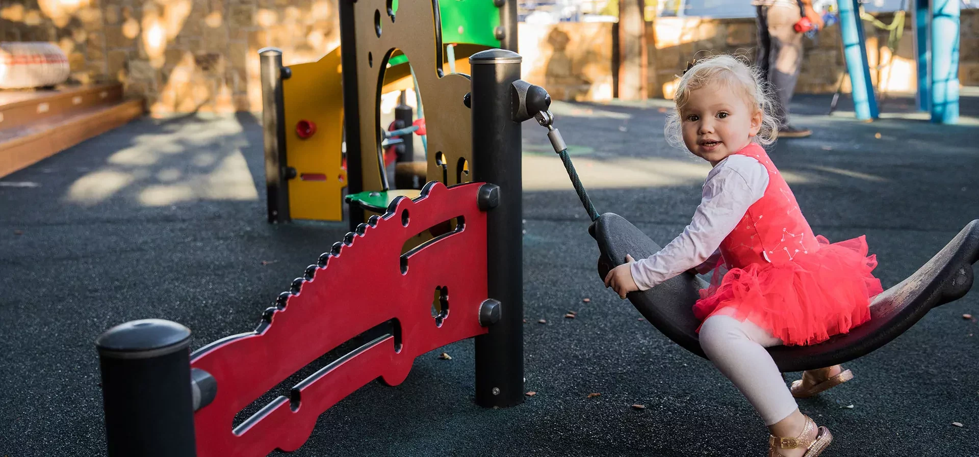 toddler playing on playground equipment for toddlers in a park