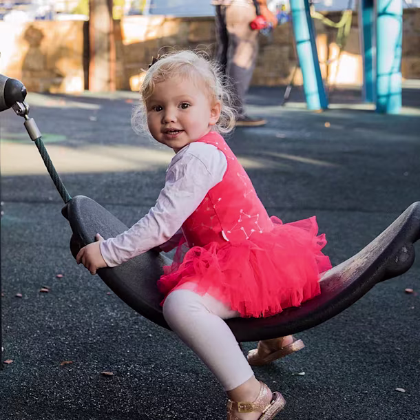 toddler playing on playground equipment for toddlers in a park