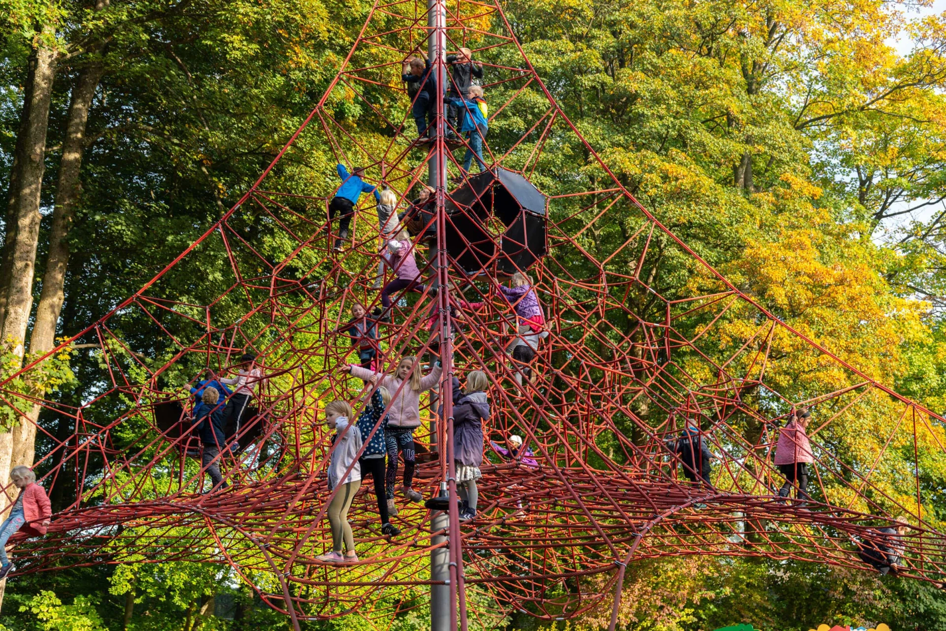 Kinder klettern auf einem großen pyramidenförmigen Netz auf dem Spielplatz am Schloss Egeskov
