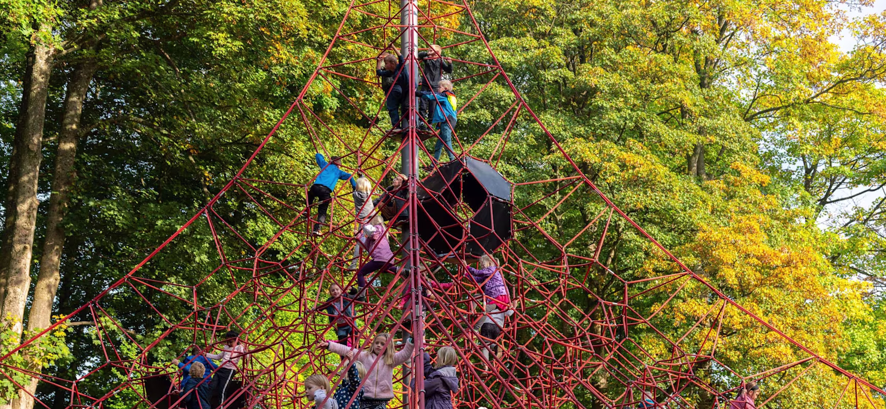 children climbing on a large pyramid shaped net on playground on Egeskov Castle