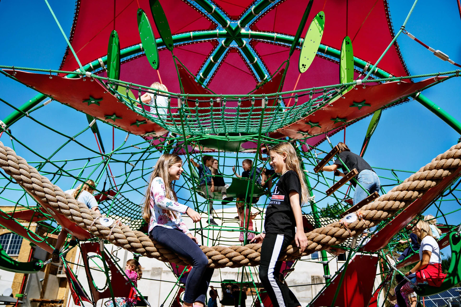 tweens playing on a giant climbing dome on a playground